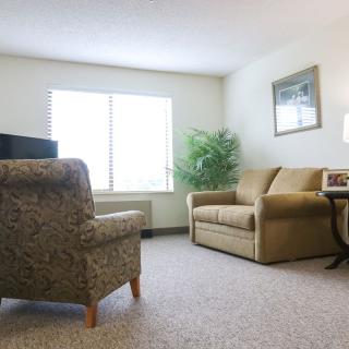 A cozy living room with a sofa, armchair, and window allowing natural light.