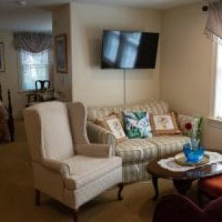 Cozy living room with a sofa, armchair, and wall-mounted TV.