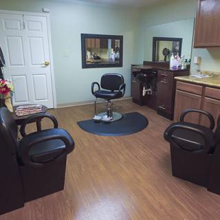 A cozy barbershop interior with a central hair cutting chair and mirrors.