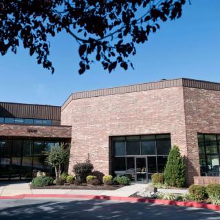 A brick building with surrounding trees under a clear blue sky.