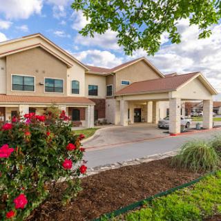 A welcoming hotel exterior surrounded by blooming flowers and a picturesque sky.