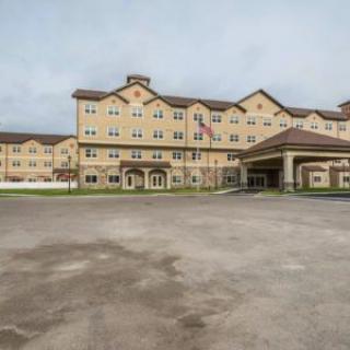 The exterior view of a large hotel with a spacious parking area.