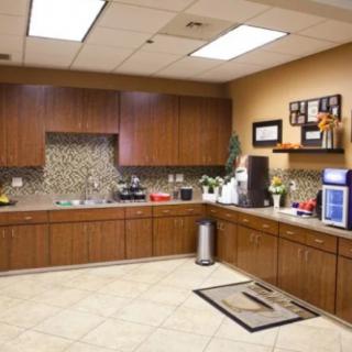 Modern office kitchen with wooden cabinets and tiled backsplash.