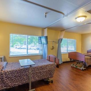 A spacious hospital room with two patient beds and large windows.