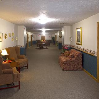 A well-lit hallway with upholstered chairs and sofas along the walls.