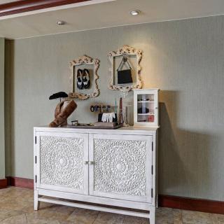 A decorated hallway with a white vintage cabinet and mirrors.