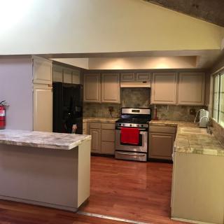 A modern kitchen with wooden floors and stone countertops.