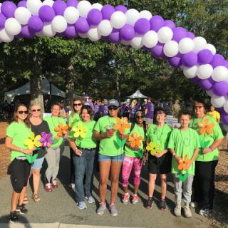 Volunteers gather together under a colorful balloon arch, ready to support their community event.
