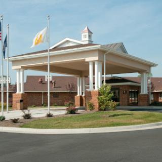 A welcoming entrance of a hospitality establishment with flags and landscaped surroundings.