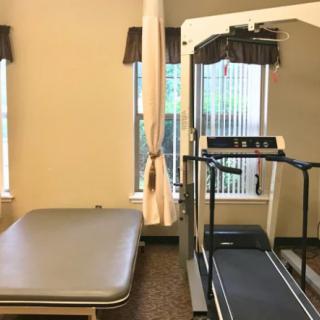 A small gym interior with a treadmill and a workout bench.
