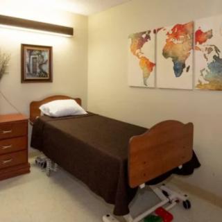 A minimalist room with a single bed, simple decor, and vibrant wall art.