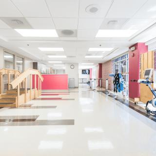 A bright and clean hospital rehabilitation area equipped with exercise machines and physical therapy tools.