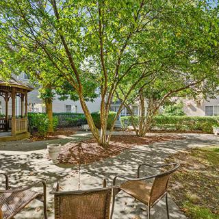 A tranquil garden with a gazebo, surrounded by trees and outdoor seating.