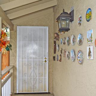 A decorated porch with wall art and a white door.