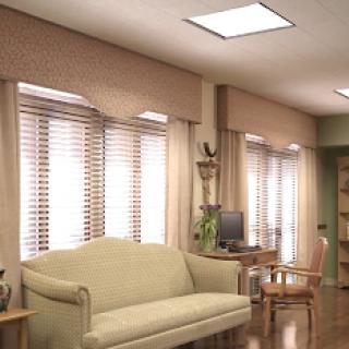 A cozy living room featuring a light-colored sofa, window blinds, and a desk in a well-lit space.