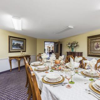 A formal dining room with an elegantly set table, featuring fine china and a floral centerpiece.