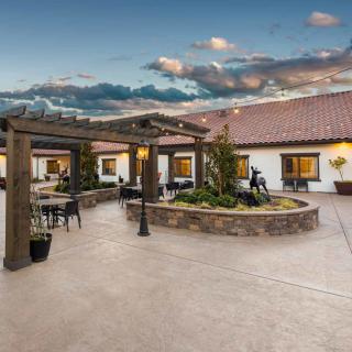 A beautifully landscaped outdoor courtyard with a pergola and seating area under a cloudy sky.