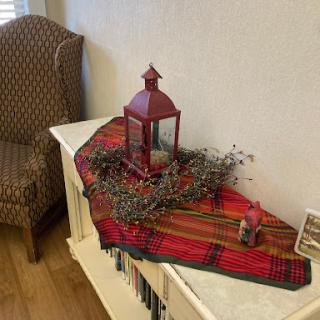 A festive table setup featuring a red lantern and a plaid runner, creating a cozy holiday atmosphere.
