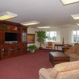 A spacious living room with comfortable sofas, a wooden entertainment center with a TV, and ample natural light from the windows.