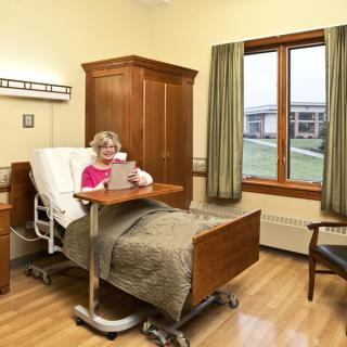 A patient in a hospital room sitting up in bed, reading a document.