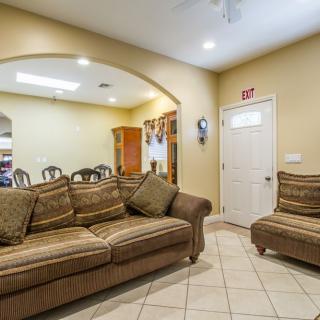 A cozy living room with a sofa and armchair, featuring tile flooring and warm lighting.