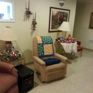 Cozy living room with a recliner, decorative quilt, and lamps.