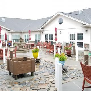 An outdoor patio area with multiple tables, chairs, a fountain, and decorative plants.