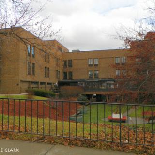 A brick residential building surrounded by autumn foliage and featuring a courtyard.