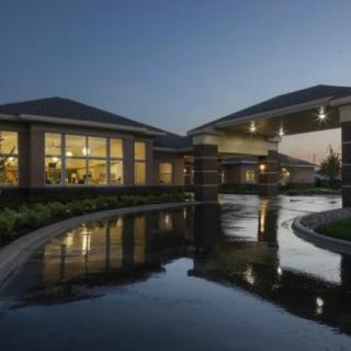A modern building with illuminated windows and a covered driveway at night.
