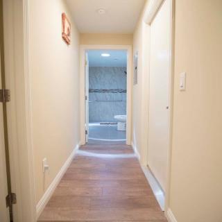 A narrow hallway with wooden flooring leads to a bathroom at the end.