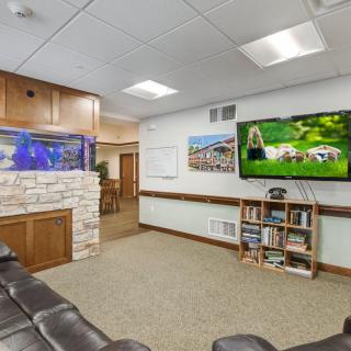 A cozy waiting room featuring a fish tank, television, and a small bookshelf for visitors.