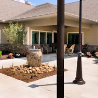 A serene outdoor patio area featuring comfortable seating, a decorative pot, and landscaped gardens.