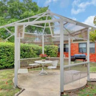 A cozy outdoor gazebo with a table and chairs, set amidst a lush garden.