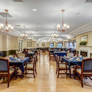 An elegant dining room with neatly set tables and chandeliers.