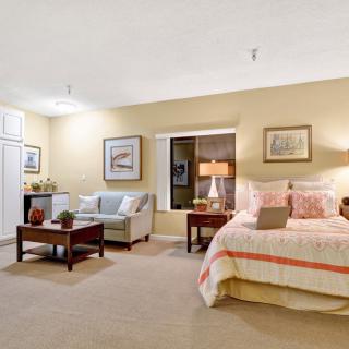 A cozy bedroom featuring a bed with striped bedding, a sofa, and decorative elements like lamps and framed pictures.