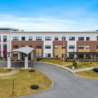 A modern hotel building with a landscaped entrance and driveway.