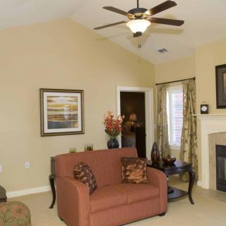 A cozy living room featuring a sofa, ceiling fan, and fireplace with elegant decor.