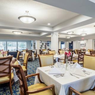 Elegantly set dining room with neatly arranged tables and chairs, featuring stylish lighting.