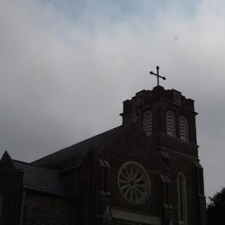 A solemn church building silhouetted against a cloudy sky.