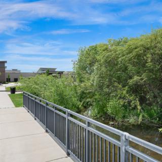 A scenic pathway with metal railings, flanked by lush greenery under a vibrant blue sky.
