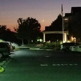 A serene evening view of a well-lit parking area with trees silhouetted against the twilight sky.