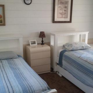 A cozy bedroom with twin beds adorned in blue bedding, separated by a wooden nightstand holding a lamp and picture frame.
