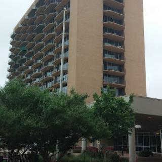 A tall apartment building featuring multiple balconies, set against a cloudy sky.