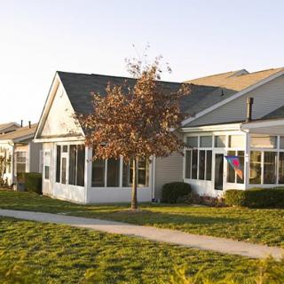 A suburban house with a well-maintained lawn and trees, lit by daylight.