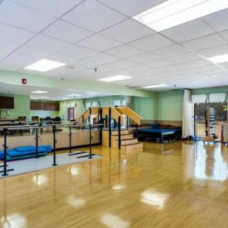 A spacious rehabilitation room equipped with parallel bars and various exercise equipment.