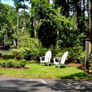 A peaceful garden scene with two white chairs surrounded by lush greenery.