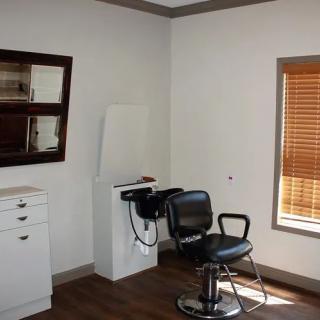 An empty salon room with a barber chair and hair washing station.