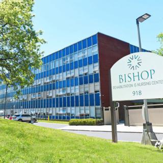 An office building with a sign labeled 'Bishop' on a sunny day.