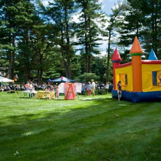 A lively outdoor festival featuring a colorful bounce house on a sunny day.