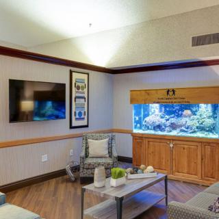 A modern living room with a large aquarium as a centerpiece, complemented by comfortable seating and a wall-mounted television.